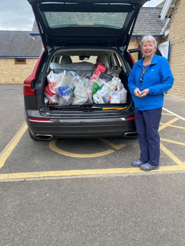 Woman standing beside an SUV filled with grocery bags.