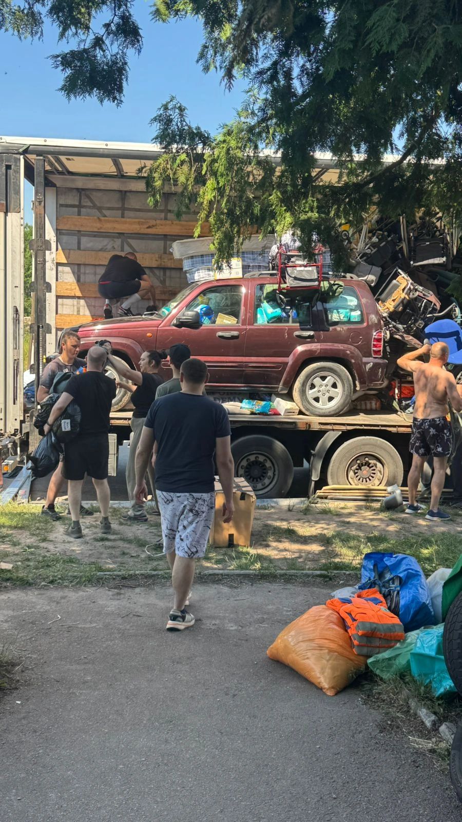 Group unloading a car and supplies from a truck.