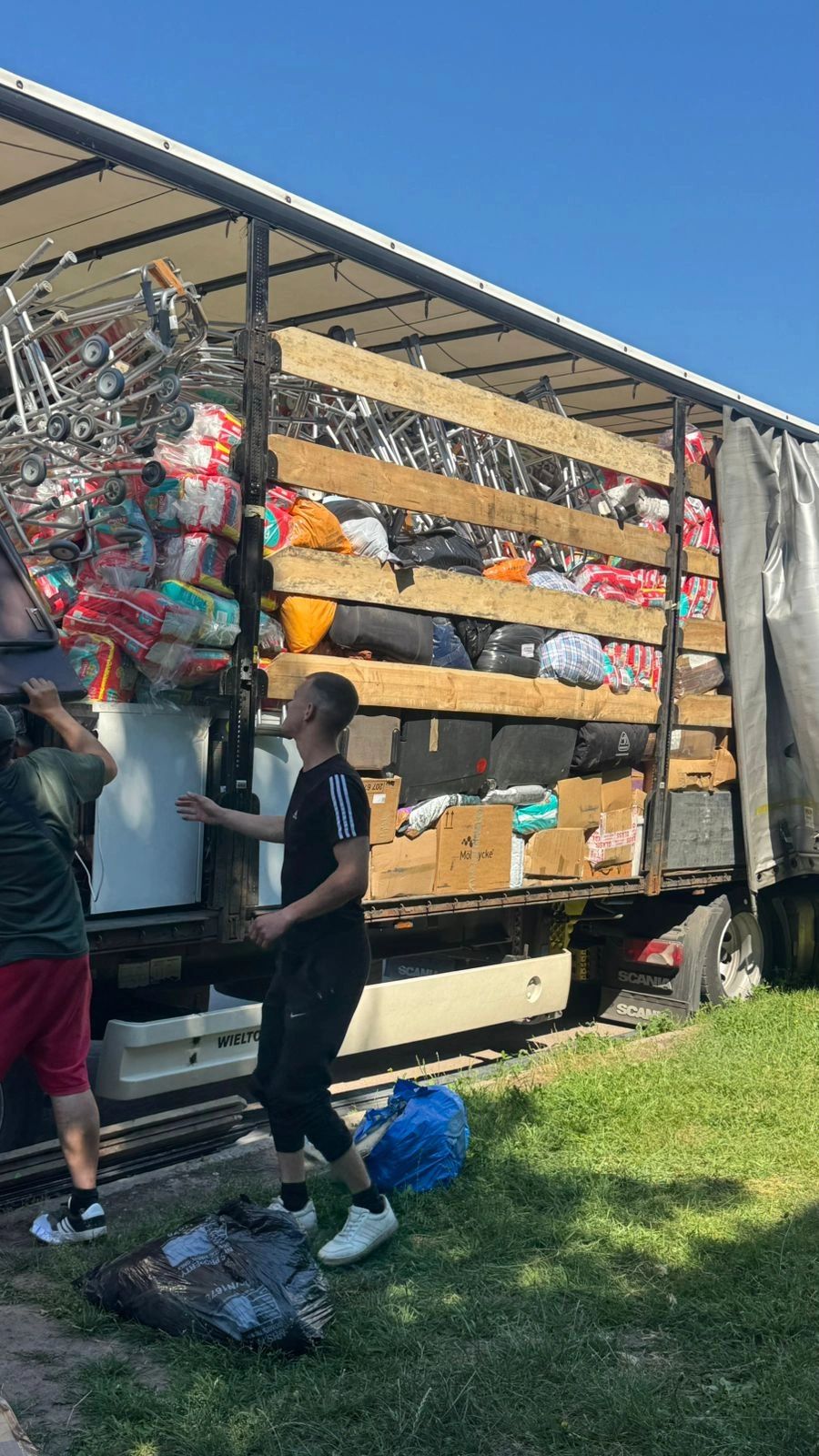 Two men unloading a truck full of goods and supplies.