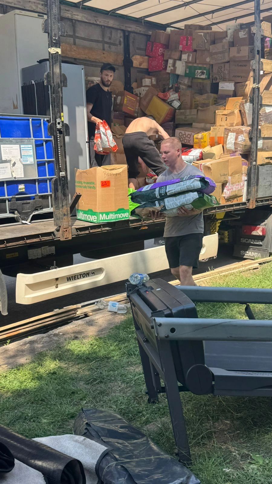 Three men unloading boxes and supplies from a truck.