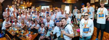 Large group celebrating with trophies and medals indoors.