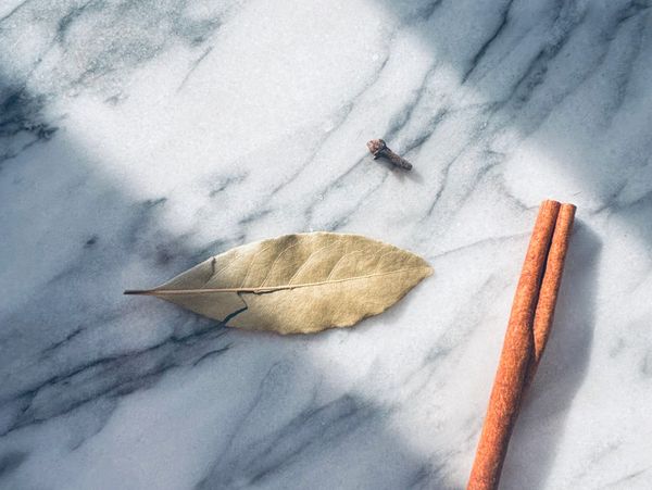 Bay leaf, clove, and cinnamon sticks on marble.