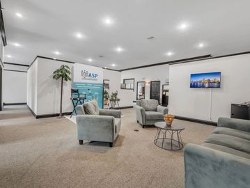 Modern office lounge with comfortable seating and a screen.