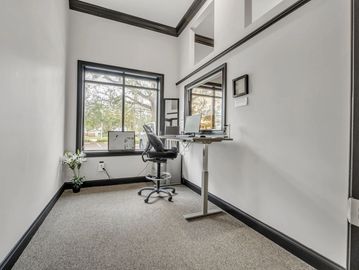 Minimalist home office with a single desk, chair, and large window.