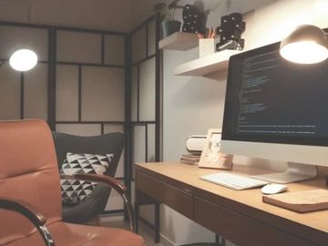Cozy workspace with a computer, leather chair, and modern decor.
