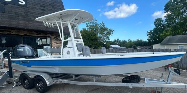 A sleek blue and white boat on a trailer under a clear sky.