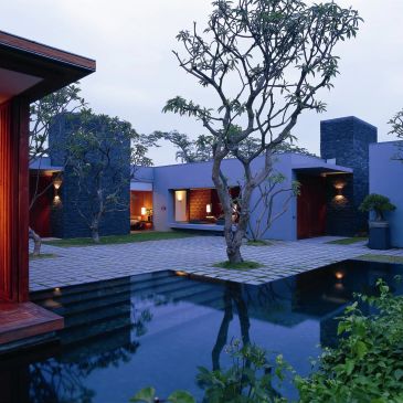 Modern house with a courtyard and reflective pool at dusk.