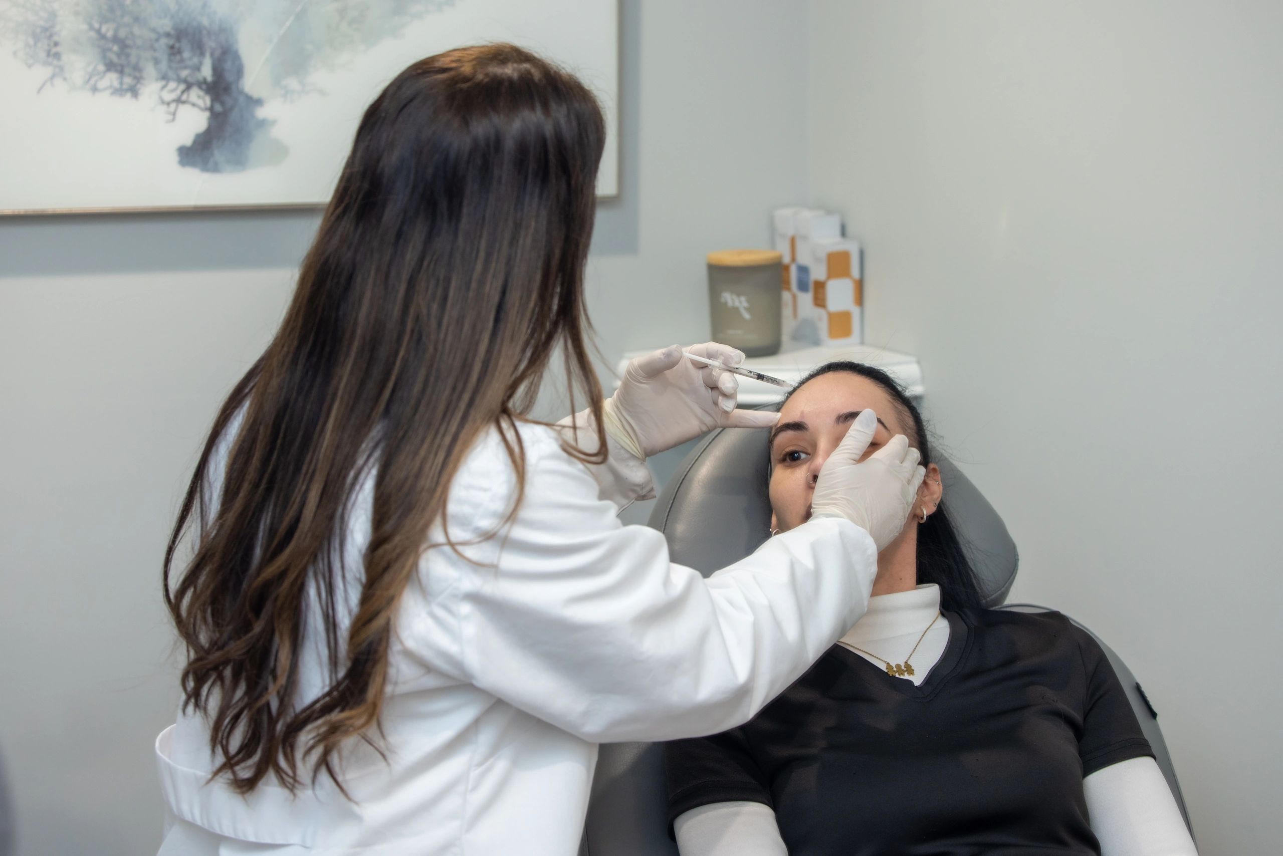 A doctor administers an injection to a patient's forehead in a clinical setting.