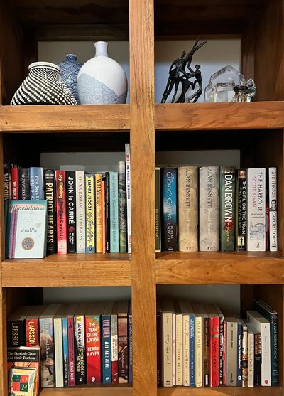 Wooden bookshelf filled with books and decorative vases and sculptures.