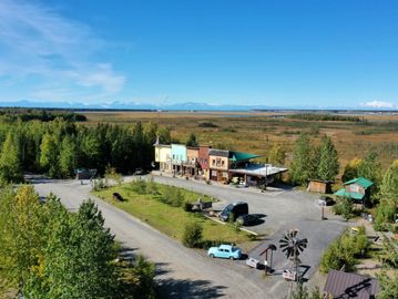 Rustic roadside stop with vintage cars and open plains under a bright sky.