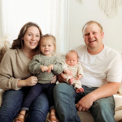 A happy family of four posing together on a couch indoors.