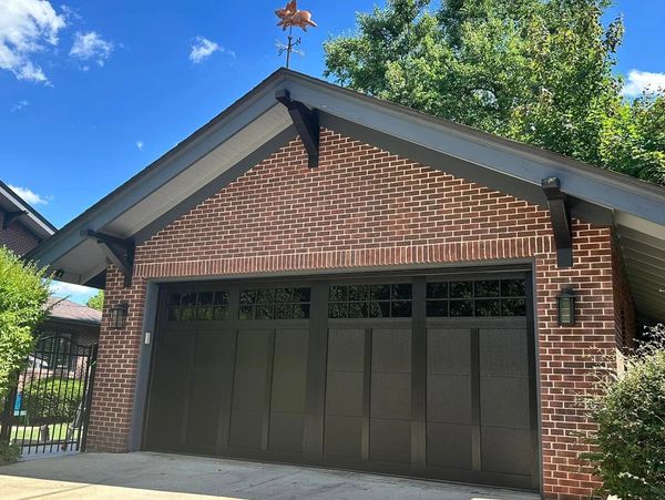 Brick garage with dark door and a pig-shaped weathervane on top.