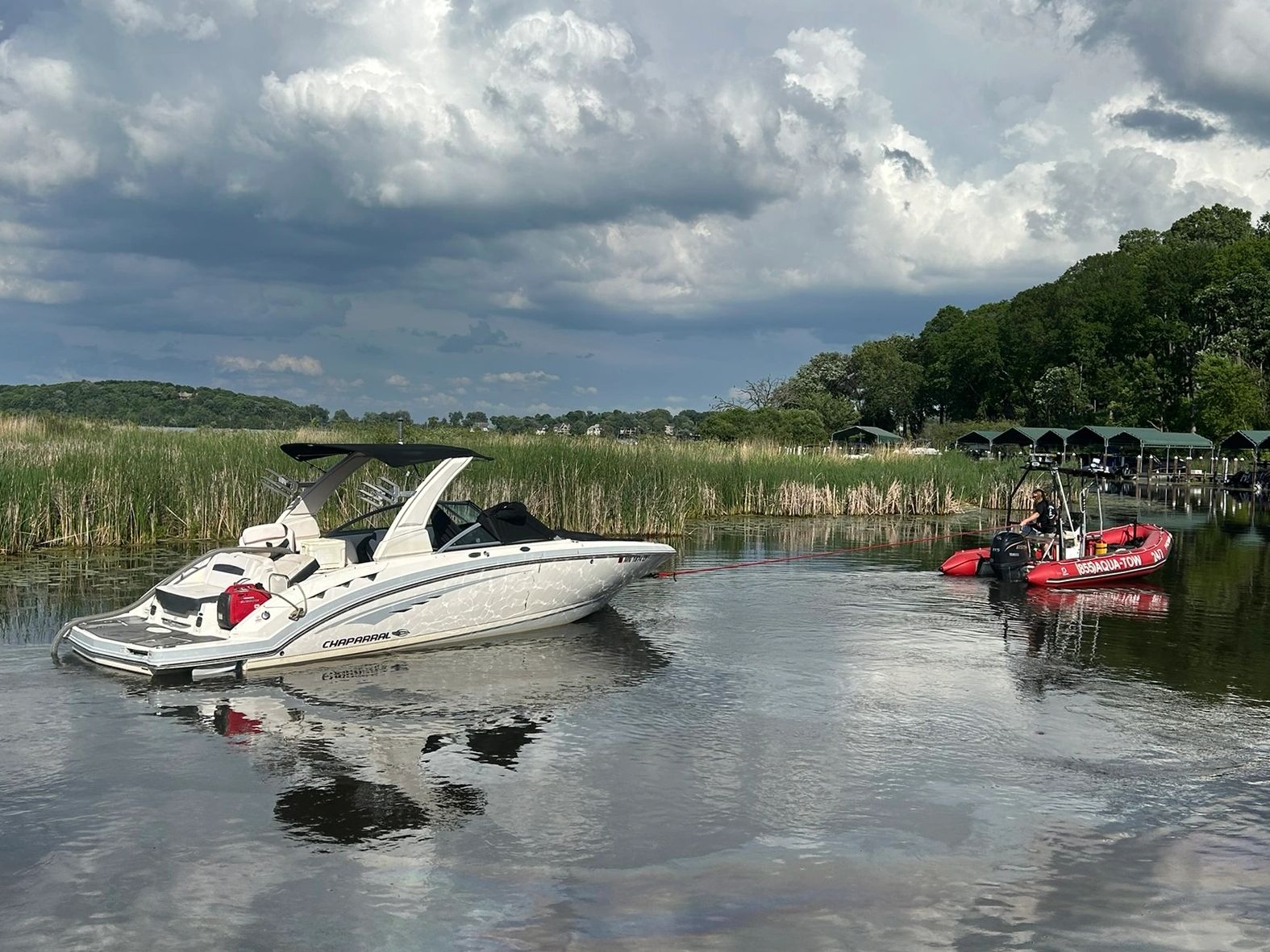 Boat being towed on a calm river under cloudy sky.