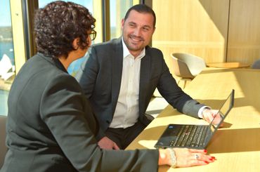 Two professionals discussing work in a bright office with a laptop.