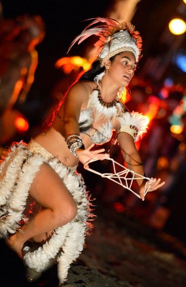 Dancer in traditional feather costume performing at night.