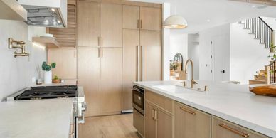 Modern kitchen with light wood cabinets and white countertops.