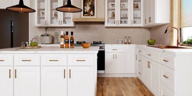 Bright modern kitchen with white cabinets and wooden floor.