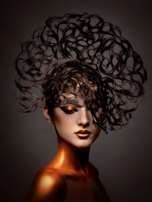Artistic portrait with intricate hair design and metallic makeup.