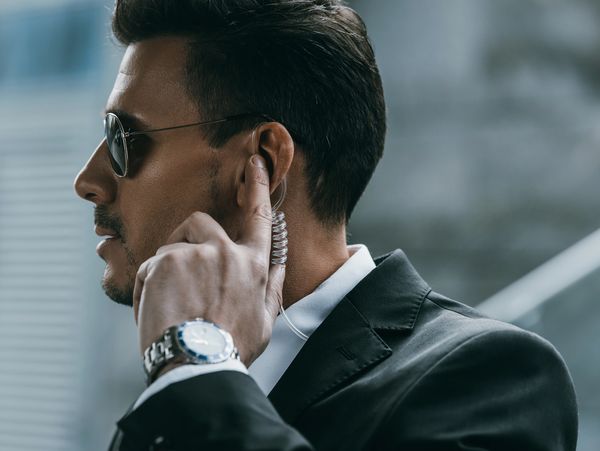 Man in suit adjusting earpiece with sunglasses on.
