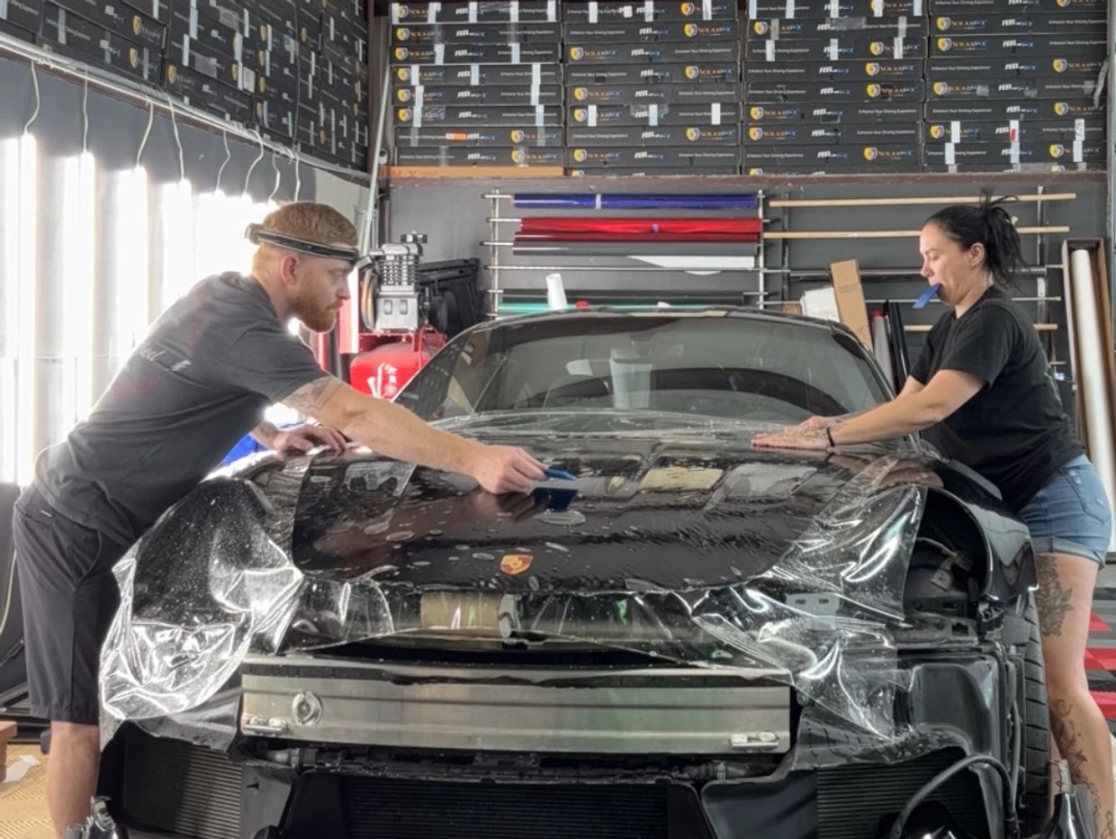 certified paint protection film technicians installing clear bra on hood of black sedan in Mckinney 