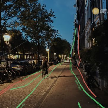 Evening street scene with cyclists and illuminated bike lanes.