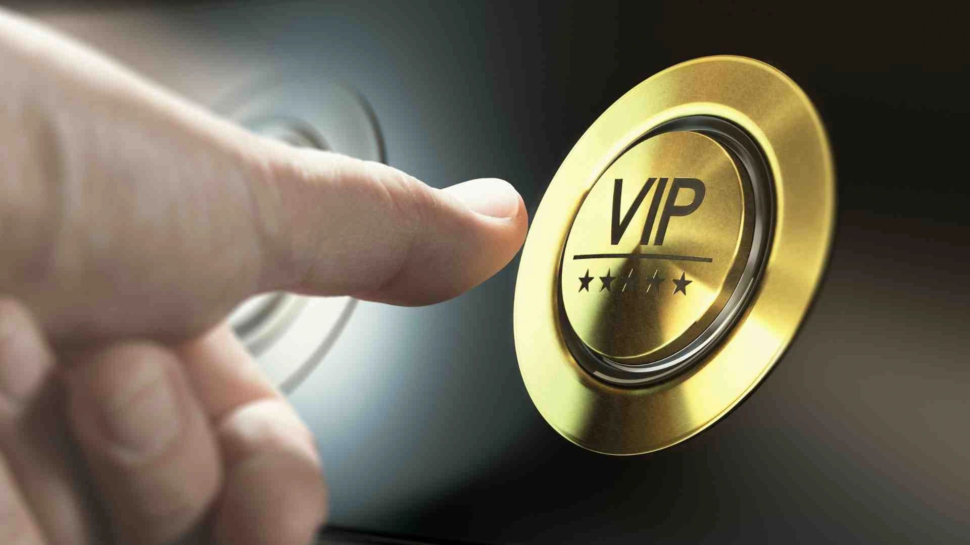 A close-up of a hand pressing a gold VIP button, symbolizing exclusivity, premium services.