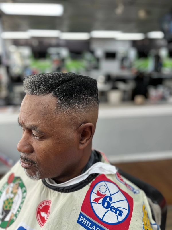 Man with a sharp, modern flat-top haircut in a barbershop.
