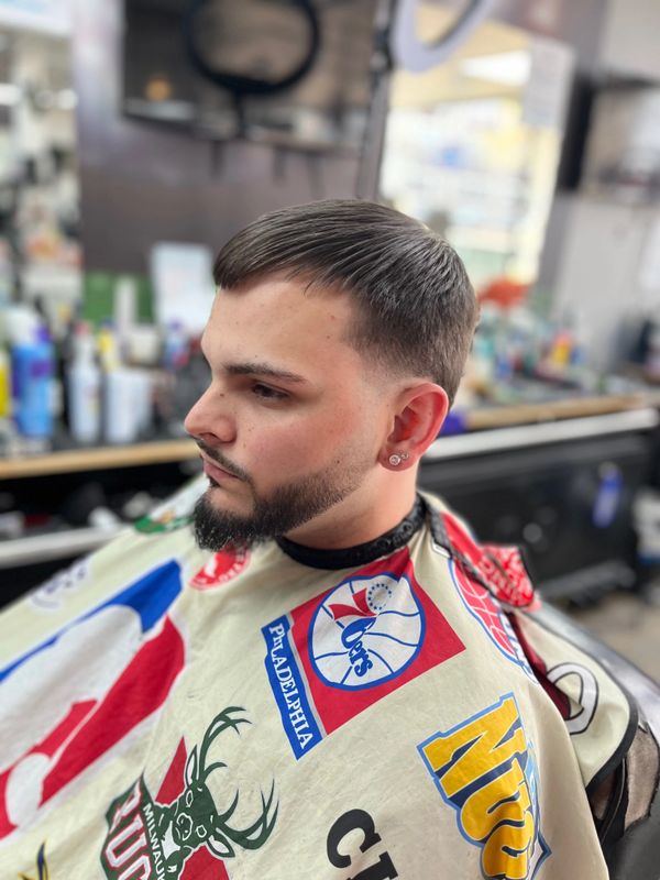 Man with a fresh haircut and beard trim at a barbershop.