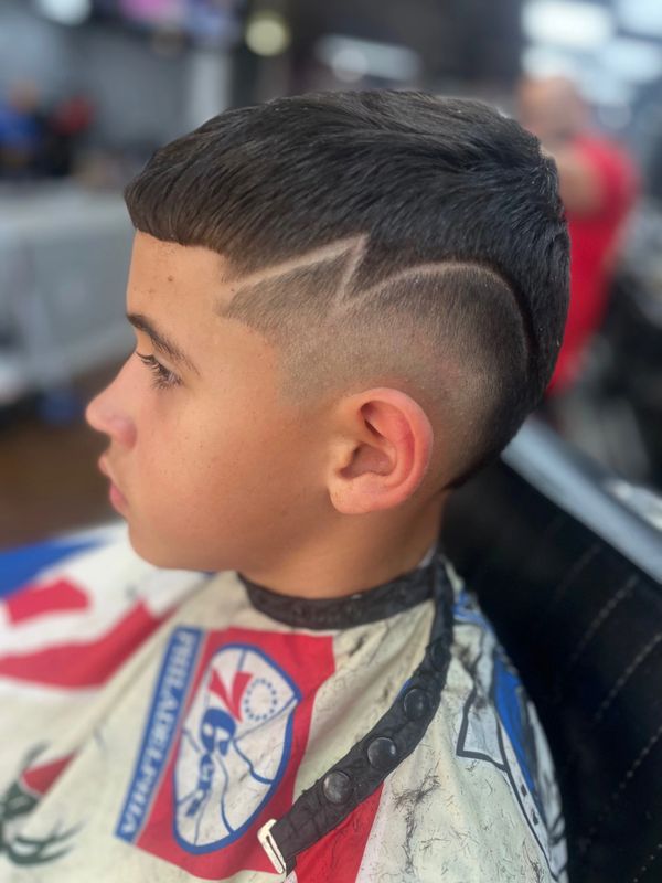 Boy with a fresh haircut featuring a zigzag shaved design on the side.