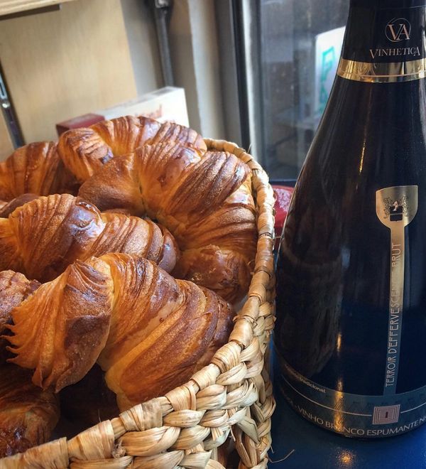 Cesta de croissants artesanais com uma garrafa de espumante da Vinhetica