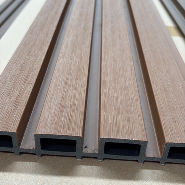 Close-up of brown composite decking boards with hollow core design.