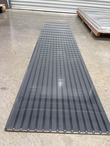 A long, transparent corrugated plastic sheet laid on a concrete floor.