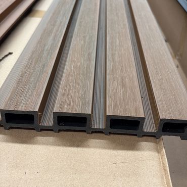 Close-up of brown composite decking boards with hollow sections.