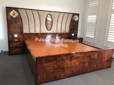 Elegant wooden bed with padded headboard and built-in nightstands in a modern bedroom.