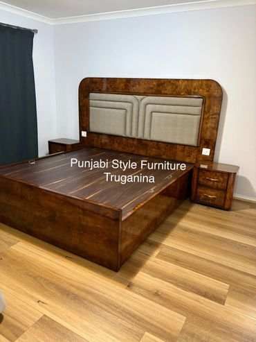 Punjabi style wooden bed with upholstered headboard and matching nightstands.