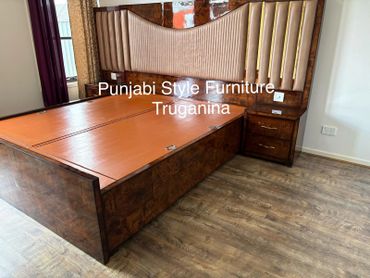 Elegant Punjabi style wooden bed with large padded headboard and side drawers.