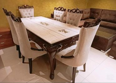 Elegant dining table set with ornate wooden chairs and tiled tabletop.