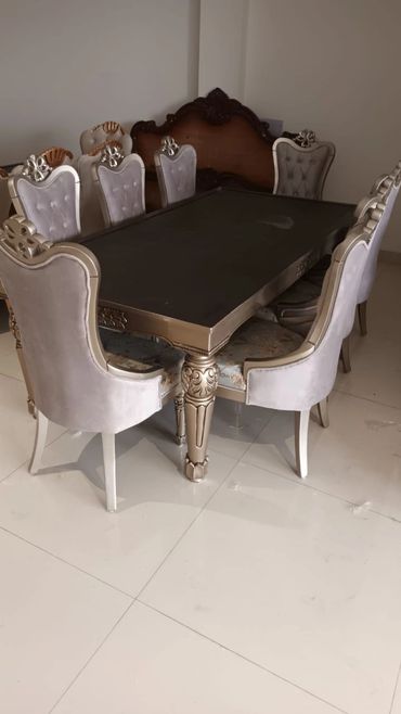 Elegant dining table set with carved wooden chairs in a spacious room.