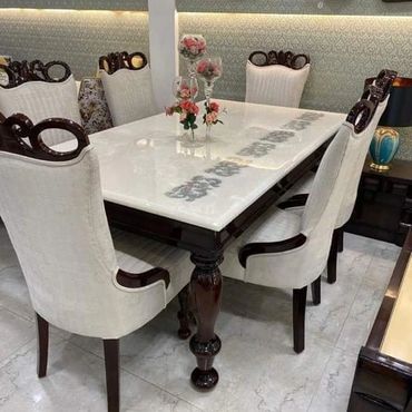 Elegant dining table with white marble top and upholstered chairs.