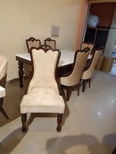 Elegant dining table set with six beige upholstered chairs.