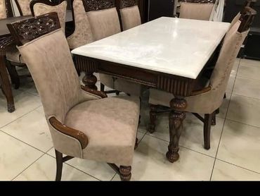 Elegant dining table set with cushioned chairs and marble top.