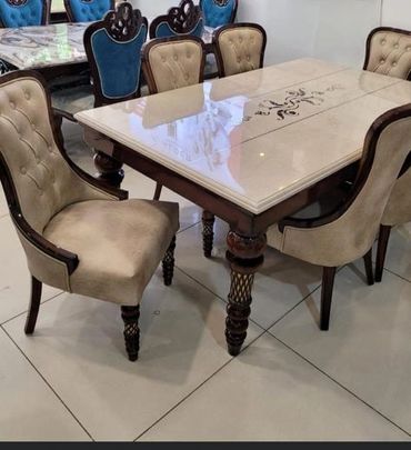 Elegant dining table set with cushioned chairs and intricate wooden legs.