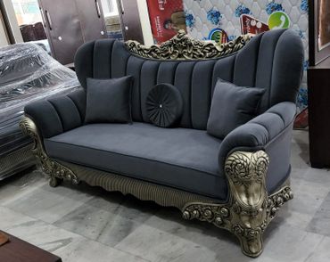 Elegant gray sofa with ornate gold detailing and plush cushions.
