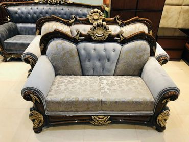 Elegant vintage sofa set with intricate wood carvings and patterned upholstery.