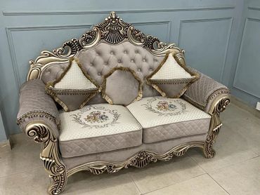 Elegant vintage-style beige sofa with intricate wooden carvings and decorative cushions.