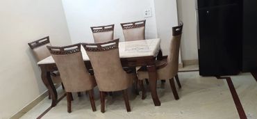 Dining table set with six beige cushioned chairs in a modern room.