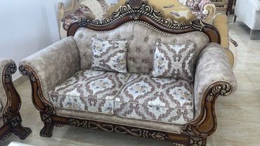 Ornate wooden sofa with floral patterned cushions and pillows.