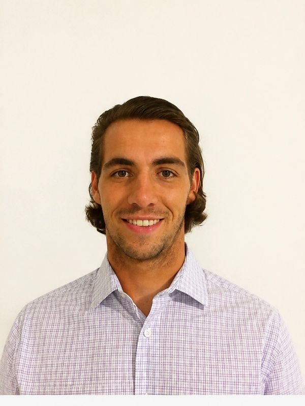 Smiling young man in a checkered shirt against a plain background.
