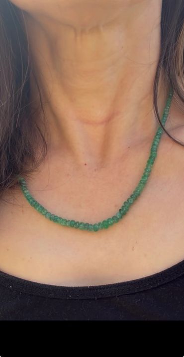 Green beaded necklace worn around the neck with a black top.
