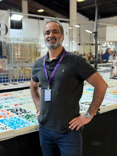 Man smiling confidently at a jewelry or bead market stall.